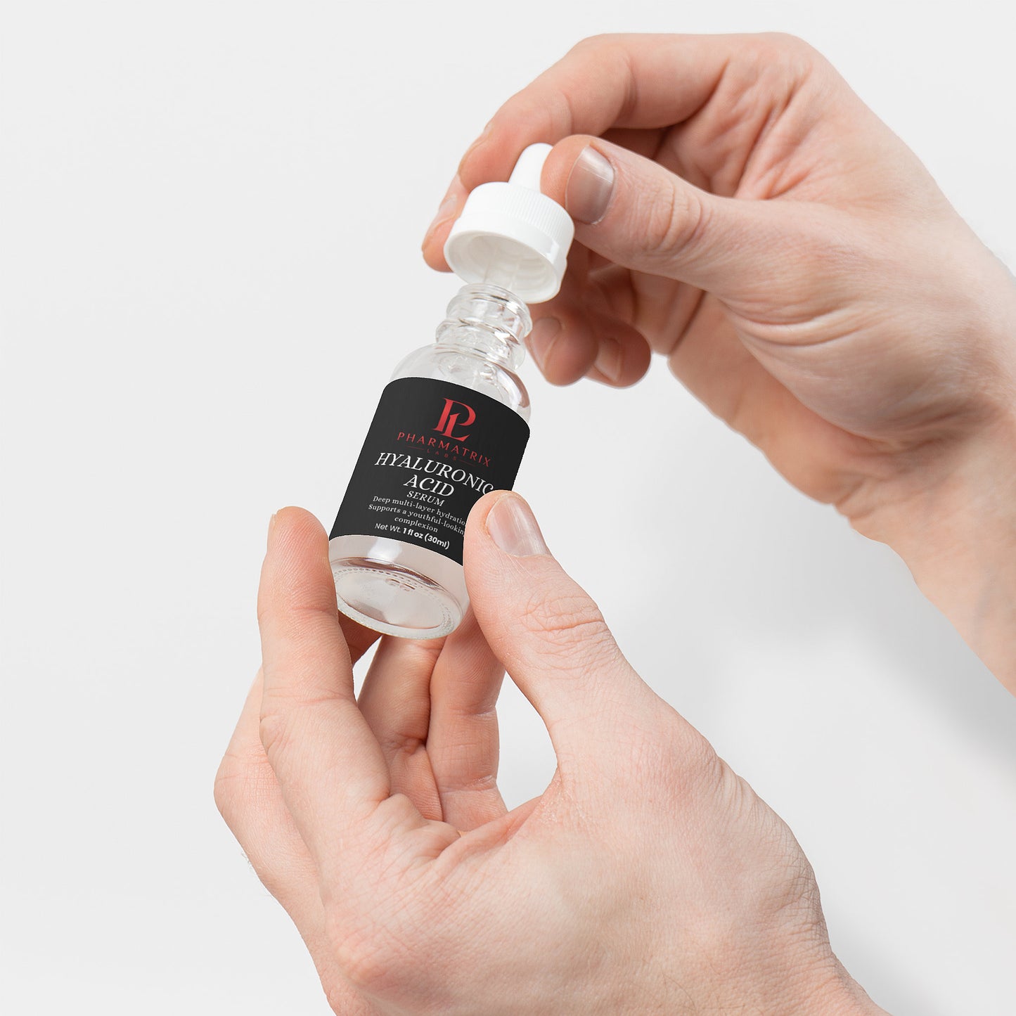Hand holding a skincare serum bottle with a white background