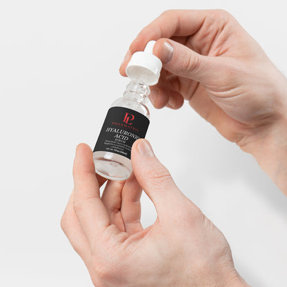 Hand holding a skincare serum bottle with a white background